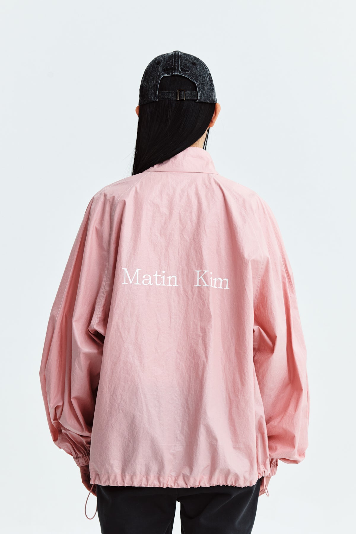 Áo khoác nữ oversize màu hồng với logo Matin Kim, có tay rộng và túi bên.