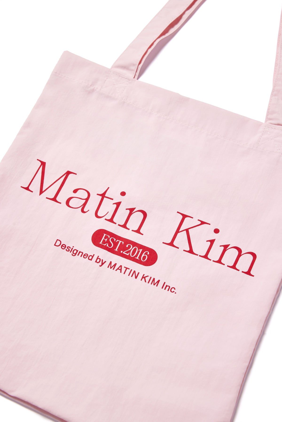 Túi tote unisex với họa tiết in và logo Matin Kim, màu hồng nổi bật.