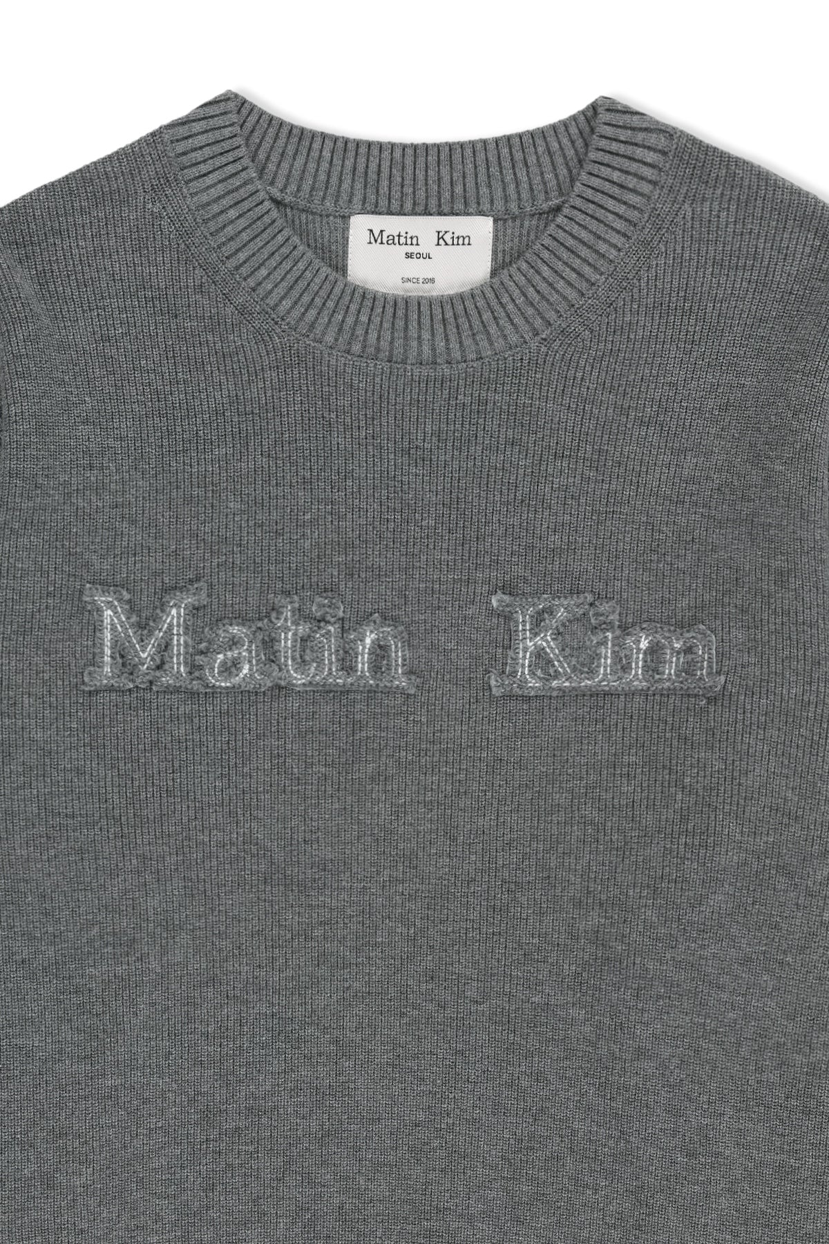 Áo len nữ màu xám, cổ tròn, tay dài, logo Matin Kim đắp vải ngang ngực.