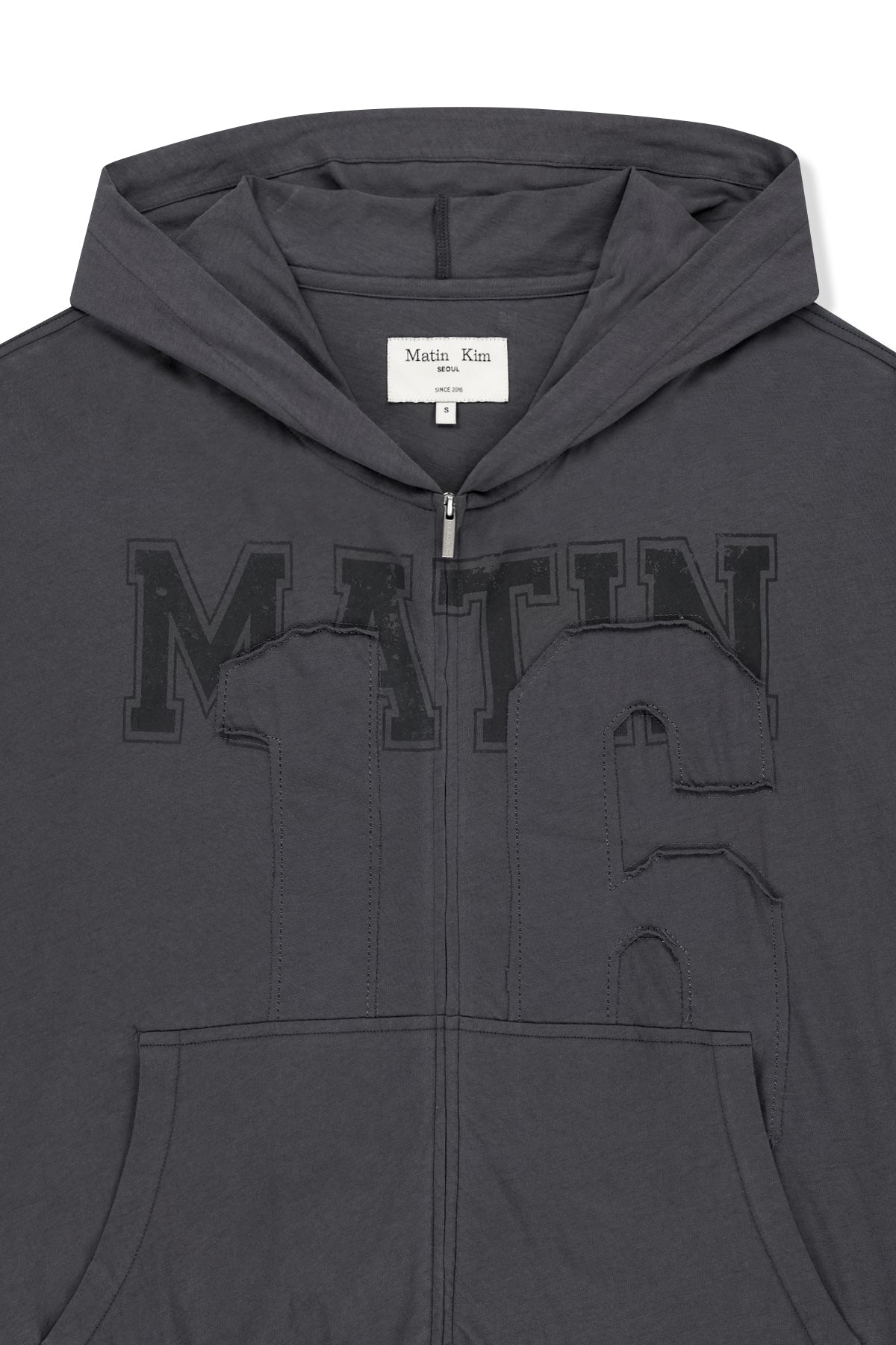 Áo khoác nữ với thiết kế hiện đại, logo Matin Kim thêu, chất liệu cotton mềm mại, và túi kangaroo tiện lợi.