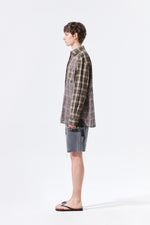 Áo sơ mi unisex với họa tiết caro, cổ sơ mi và tay cài nút, kiểu dáng oversize.
