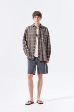 Áo sơ mi unisex với họa tiết caro, cổ sơ mi và tay cài nút, kiểu dáng oversize.