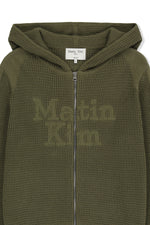Áo sơ mi unisex màu khaki có mũ trùm, khóa kéo giữa trước, tay dài và logo Matin Kim