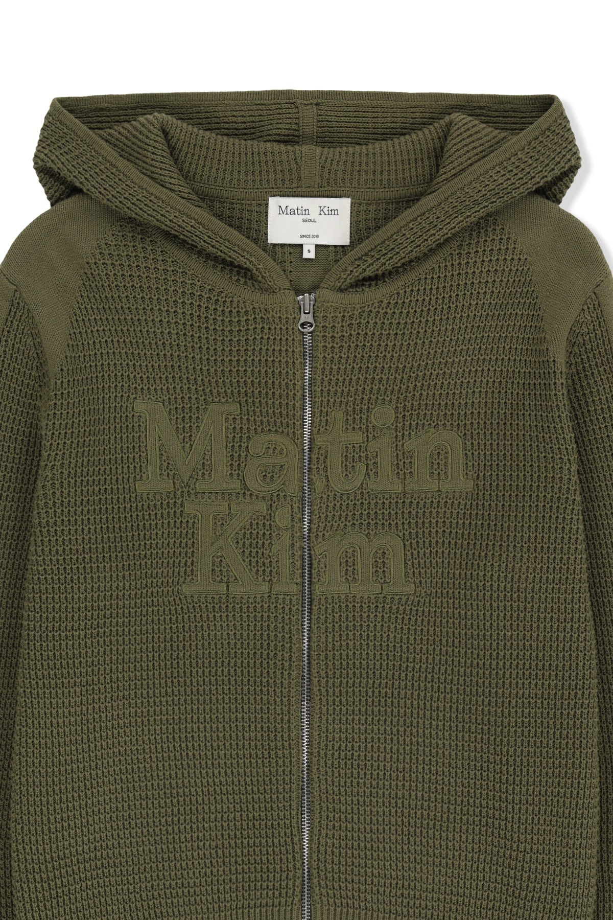 Áo sơ mi unisex màu khaki có mũ trùm, khóa kéo giữa trước, tay dài và logo Matin Kim