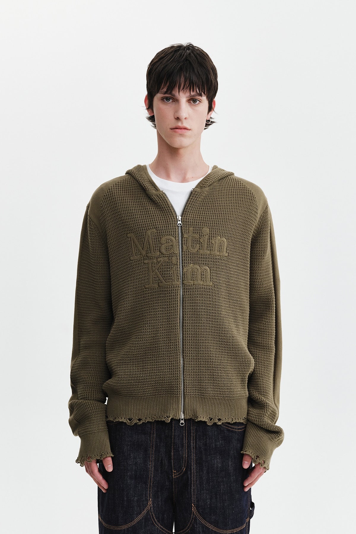 Áo sơ mi unisex màu khaki có mũ trùm, khóa kéo giữa trước, tay dài và logo Matin Kim