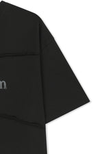 Áo top unisex với đường cắt chéo và logo Matin Kim, phom hộp màu đen.