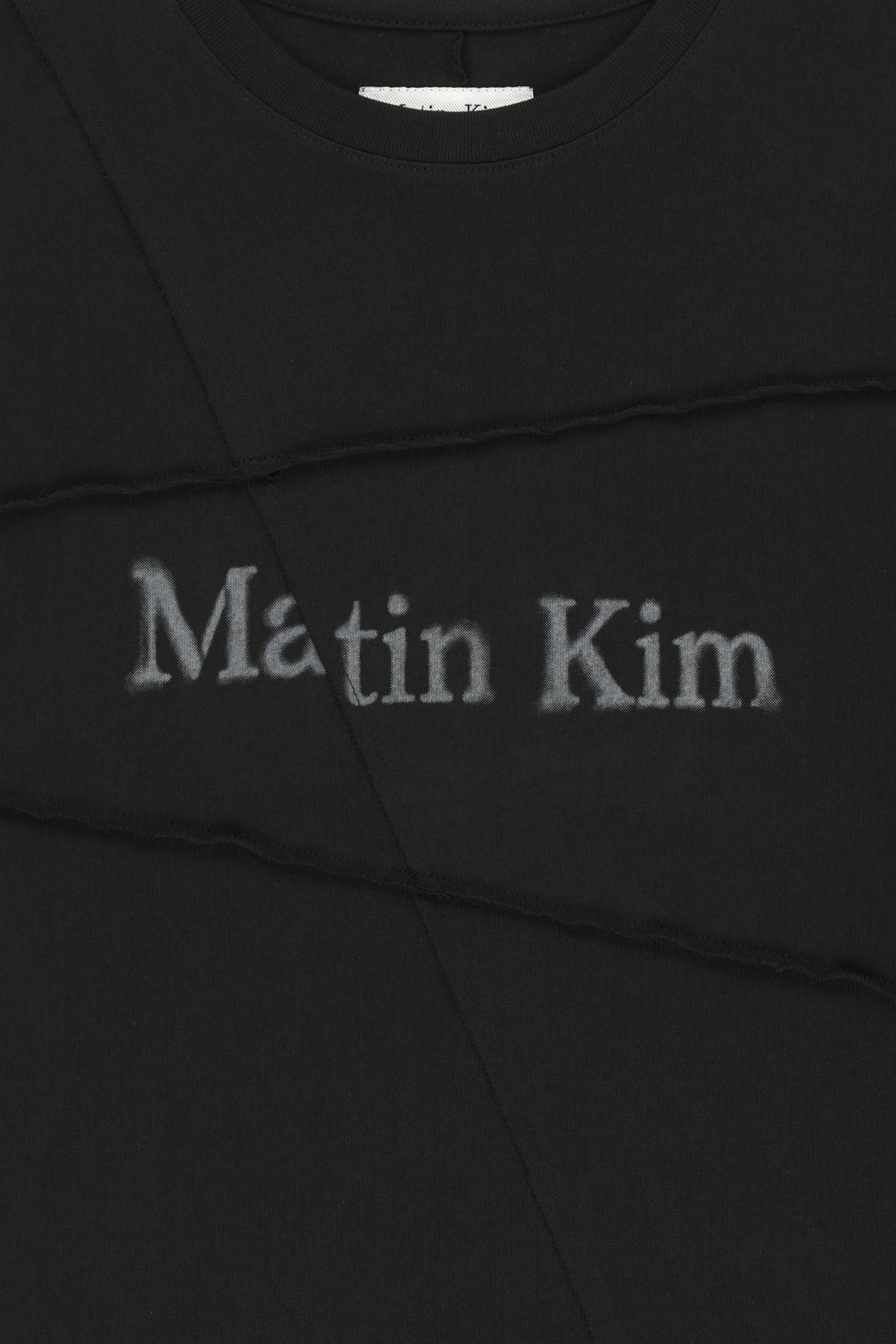 Áo top unisex với đường cắt chéo và logo Matin Kim, phom hộp màu đen.